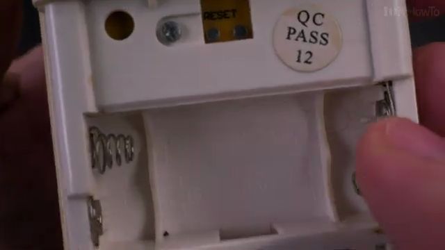 Inserting fresh AAA batteries into remote with correct polarity