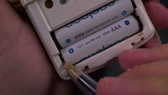 Using a ballpoint pen tip to pop out stuck AAA battery
